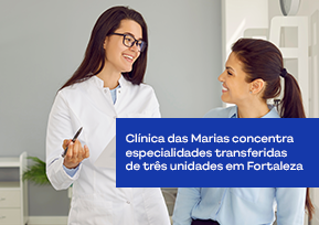Médica conversa com paciente e faz anotações no consultório.