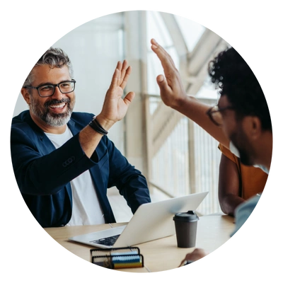 Dois profissionais comemoram com um high five durante uma reunião, celebrando uma conquista conjunta.