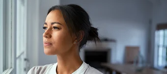 Mulher pensativa olhando para o horizonte com semblante sério